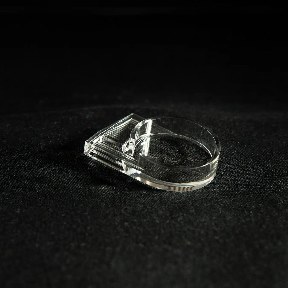 Clear acrylic ant-keeping accessory photographed on a dark background