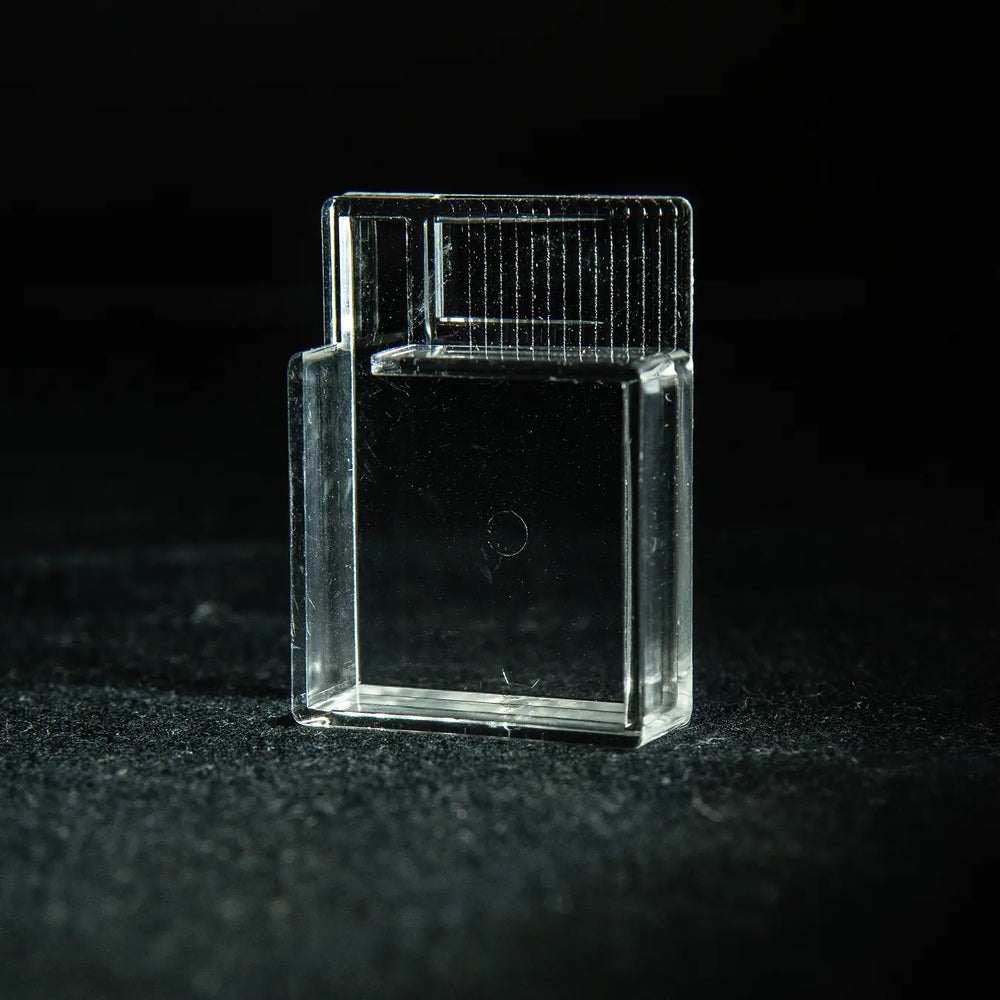Clear acrylic ant-keeping accessory photographed on a dark background